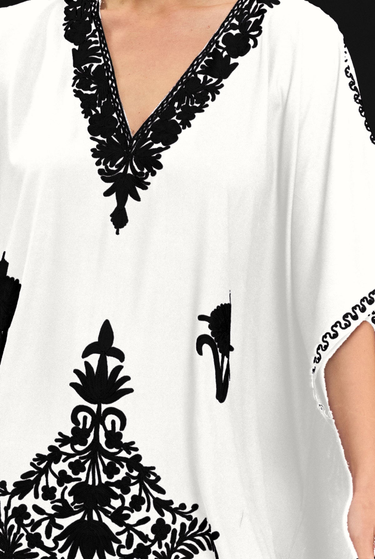 Close-up of the hand-embroidered V-neckline on the white Kashmir cotton kaftan, black threadwork