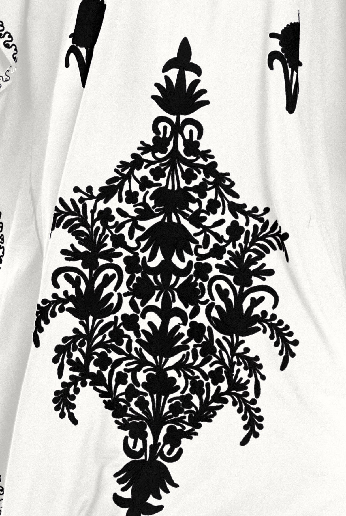Detail of the black hand-embroidered floral panel on the white Kashmir cotton kaftan