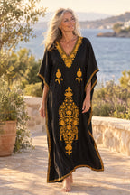 Woman wearing the black and mustard Kashmir cotton kaftan on a coastal terrace at golden hour