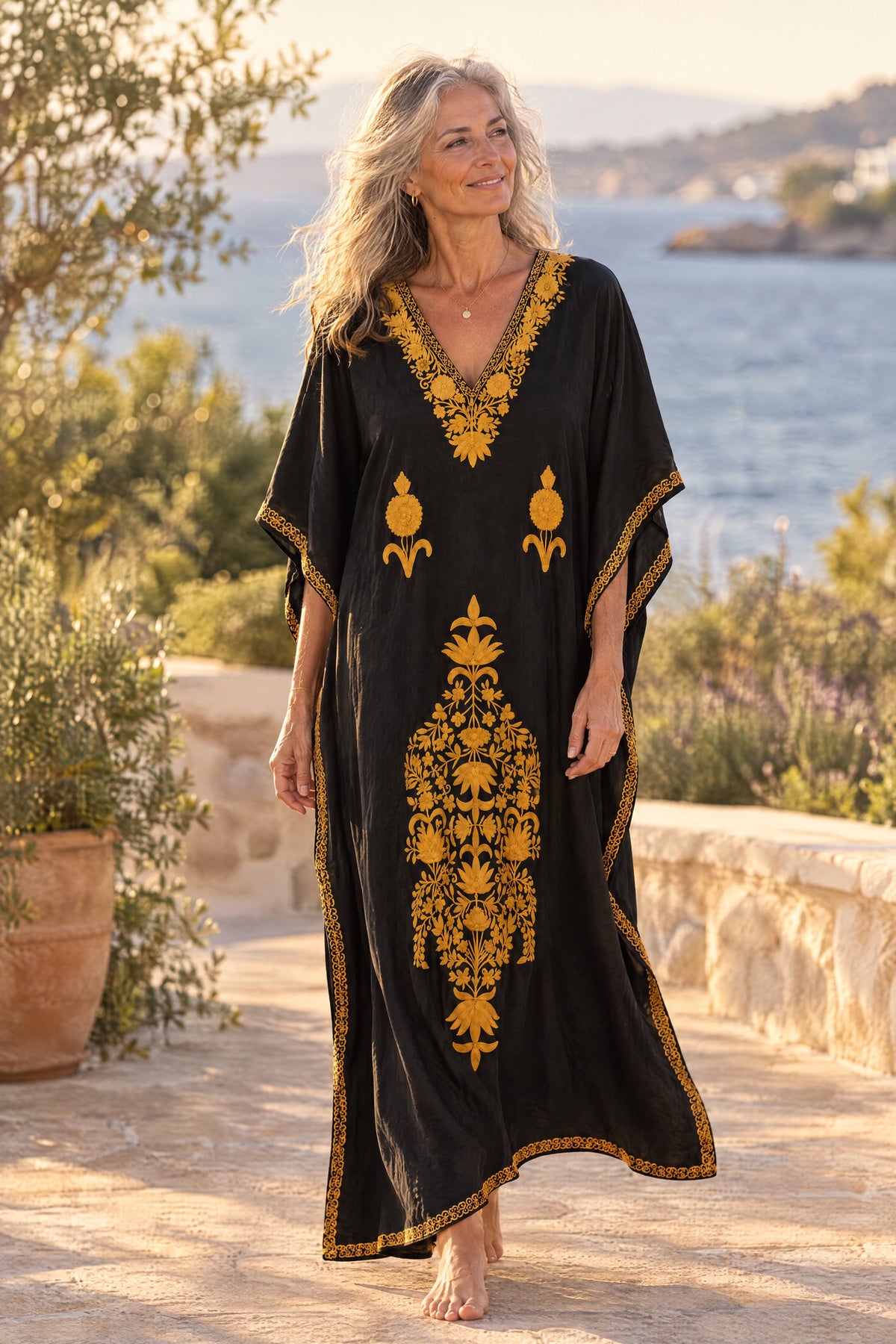 Woman wearing the black and mustard Kashmir cotton kaftan on a coastal terrace at golden hour