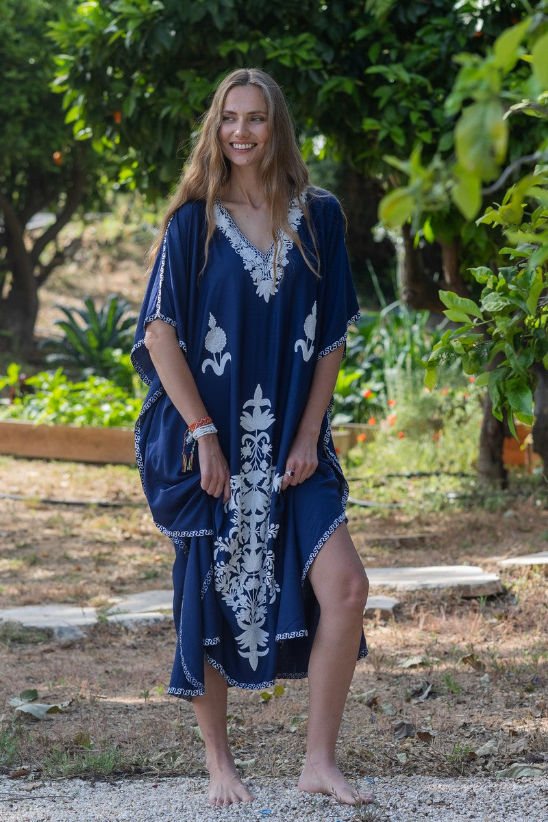 Woman wearing a blue Miraya Cove catftan dress with white patterns in an outdoor setting